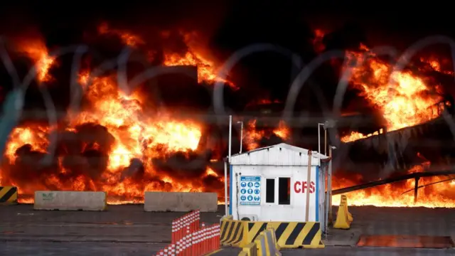 A white shed stands in front of a blaze