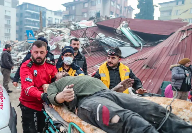 Emergency workers carry a man out of the ruins of a collapsed building on a stretcher, 52 hours after the earthquake struck