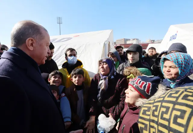 Turkish President Recep Erdogan speaks to a group of children and a woman while visiting the city of Kahramanmaras in the aftermath of the February 2023 earthquake