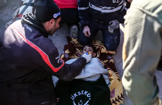 Eleven-year-old Ahmet Findik is given water from a bottle cap by his father after being rescued