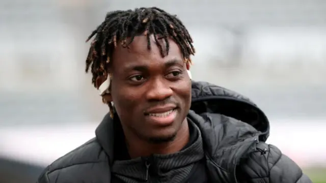 Footballer Christian Atsu seen ahead of a game for Newcastle United. He's wearing a black coat and a pair of earphones