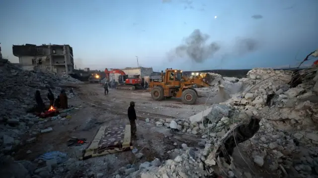 Rescuers search for survivors under the rubble of a collapsed building after an earthquake, in Idlib, Syria