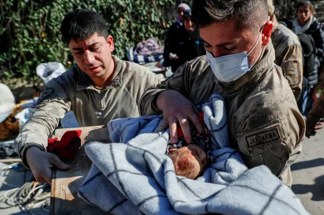 A rescuer carries a 20-day-old baby who survived the quake