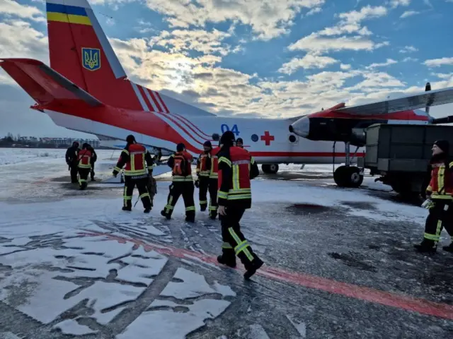 Ukrainian State Emergency Service walk towards the aid plane