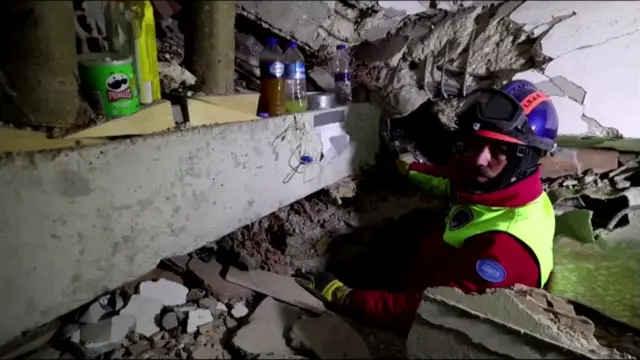 A rescue worker shows the tube he is using to communicate with a woman trapped under the rubble