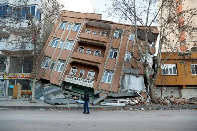 A man walks past a partially collapsed building, in the aftermath of a deadly earthquake, in Pazarcik, Turkey February 9, 2023