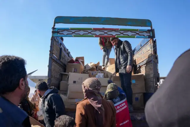 Syrians receive aid at a make-shift shelter near the rebel-held town of Jindayris