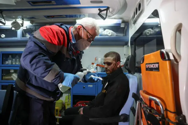 A man is treated at the scene by a paramedic