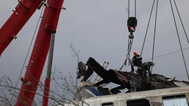 Closeup of emergency workers with cranes at the site of a train crash in Greece