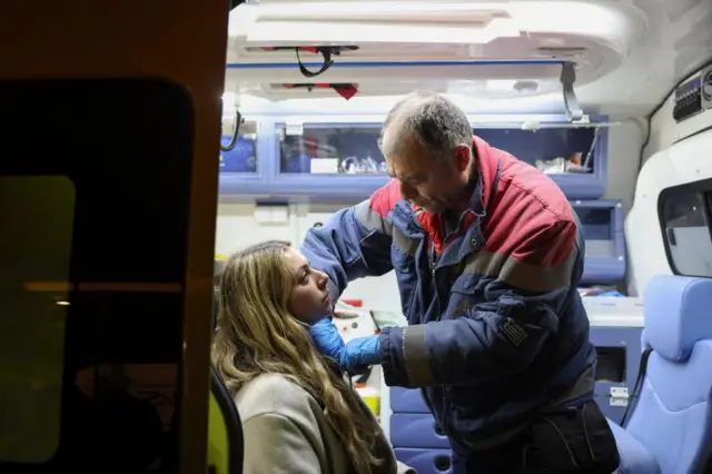 a woman is treated by a paramedic at the scene