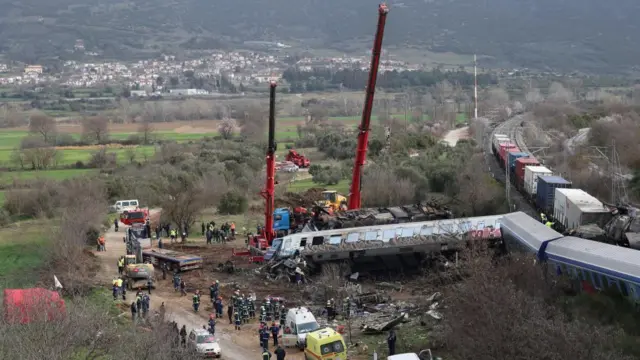 Wide shot of emergency workers with cranes at the site of a train crash in Greece