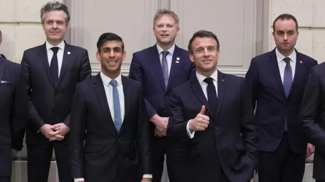 Emmanuel Macron flashes a thumbs-up as he stands next to Rishi Sunak