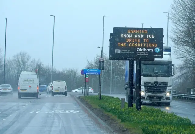 dot matrix sign on the roadside warning of snowm ice and poor driving conditions, in Oldham