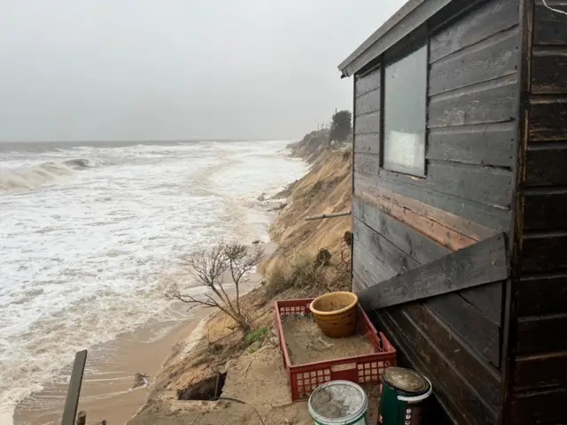 One of the wooden huts that might fall into the sea