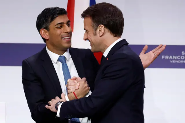 Rishi Sunak and Emmanuel Macron shake hands and embrace