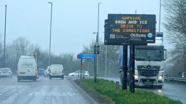 A dot matrix sign on the roadside warning of snowm ice and poor driving conditions, in Oldham, Greater Manchester