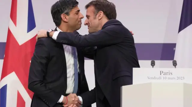 Rishi Sunak and Emmanuel Macron embrace