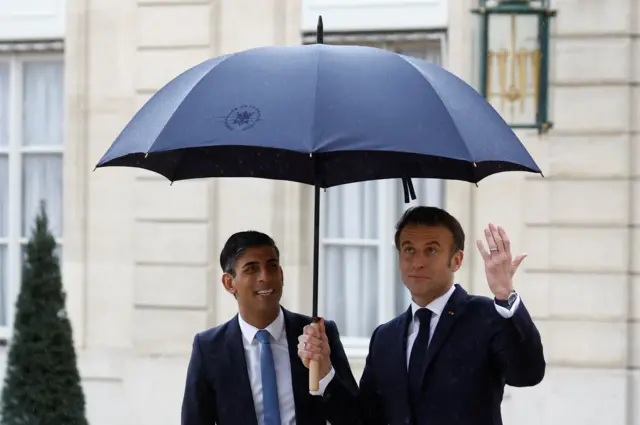 Rishi Sunak and Emmanuel Macron under an umbrella