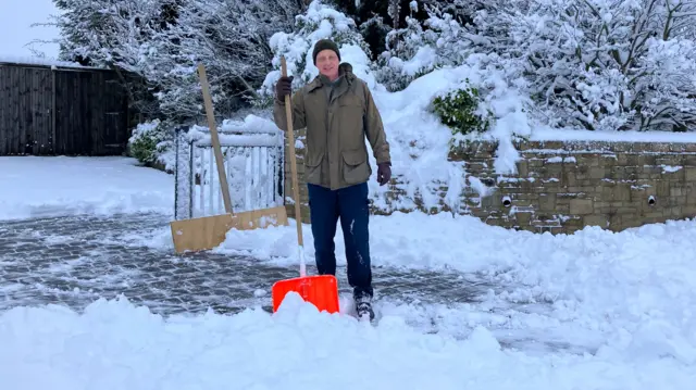 Nick Weston stands on his drive with a snow shovel