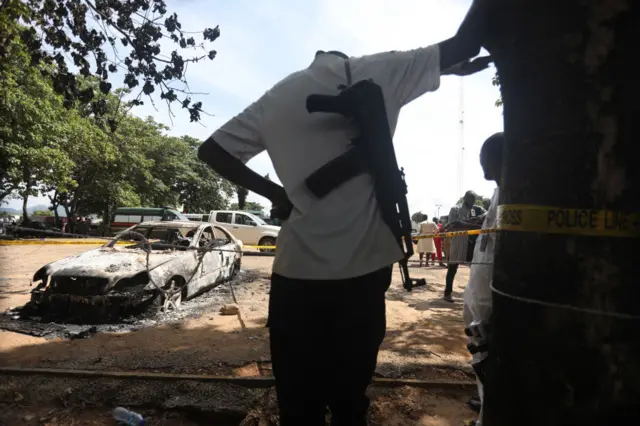 A police officer stands beside a burnt prison vehicle in Abuja, Nigeria on July 6, 2022