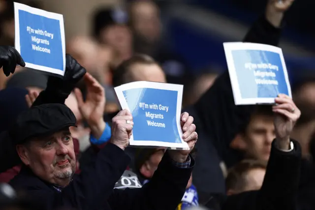 Fans holding 'I'm with Gary migrants, welcome' signs in Leicester