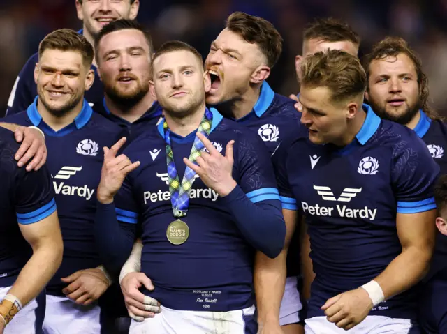 Scotland players celebrate after the match as Jack Dempsey bites the ear of Finn Russell