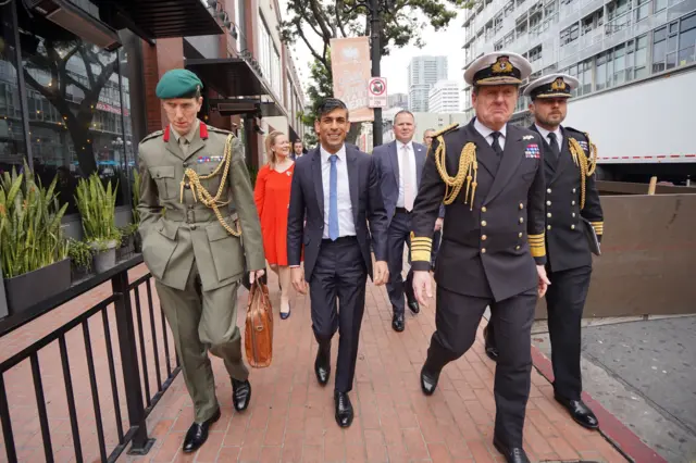 Rishi Sunak walking with military personnel