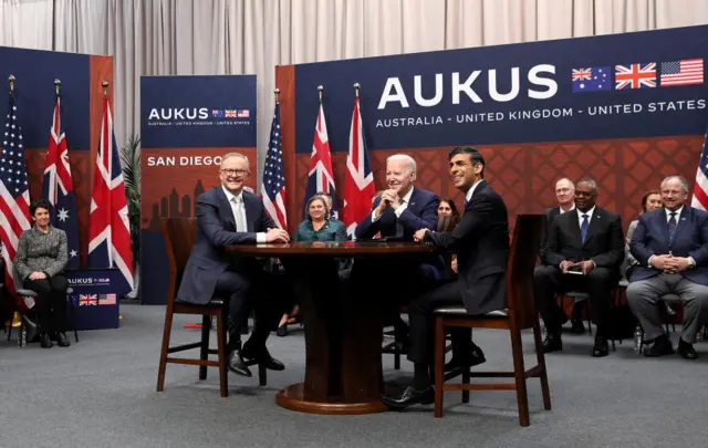 Joe Biden, Rishi Sunak and Anthony Albanese pose for a photo at a table following their meeting