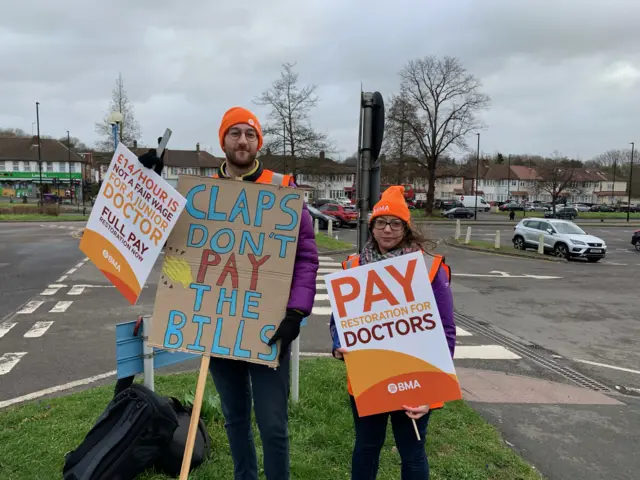 Two doctors holding signs