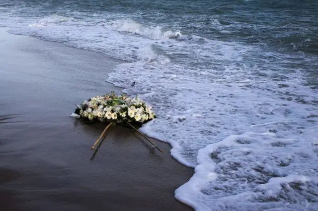 A wreath of flowers floats on the Mediterranean Sea, thrown by people who ended a protest march on the beach at the site of the shipwreck on March 11, 2023