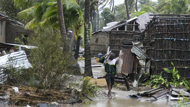 A man collects some wood on a flooded street near Quelimane, as the storm Freddy hits Mozambique, 12 March 2023.