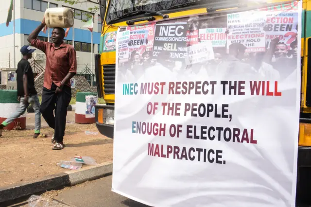 A man walk past a banner of the People's Democratic Party (PDP) during a protest at Independent National Electoral Commission (INEC)