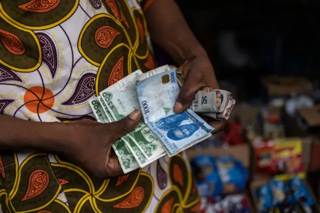 A vendor shows old and newly introduced Nigerian Naira banknotes in a market in Lagos on February 16, 2023.