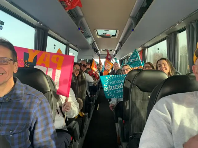 Striking teachers waving flags on a coach bound for London