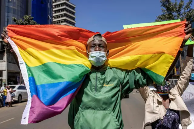 A man holds a rainbow flag during a protes