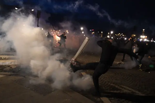 A protester wearing black runs through tear gas