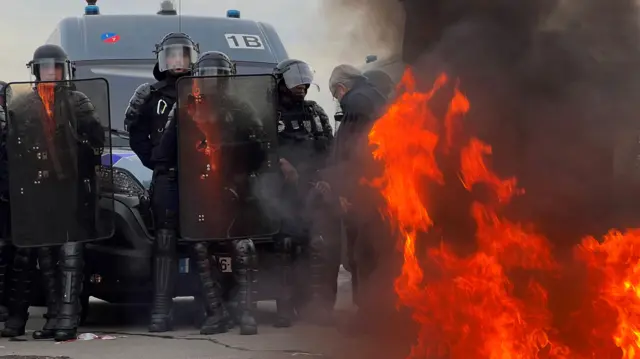 French gendarmes and CRS riot police stand on position near a fire as demonstrators gather on Place de la Concorde