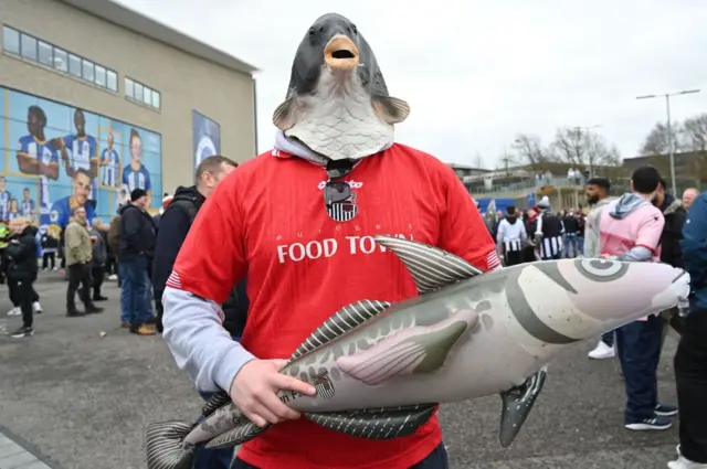 A Grimsby fan with an inflatable fish and fish head covering