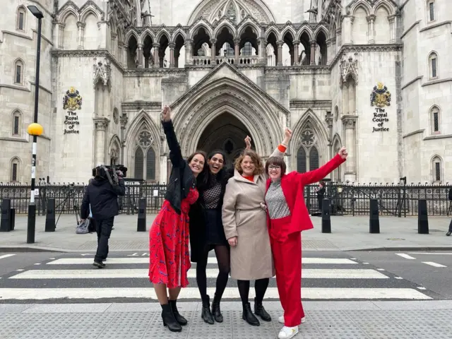 Four women in front of the Royal Courts of Justice