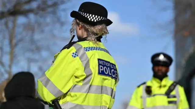 A female police officer stands with her back to the camera