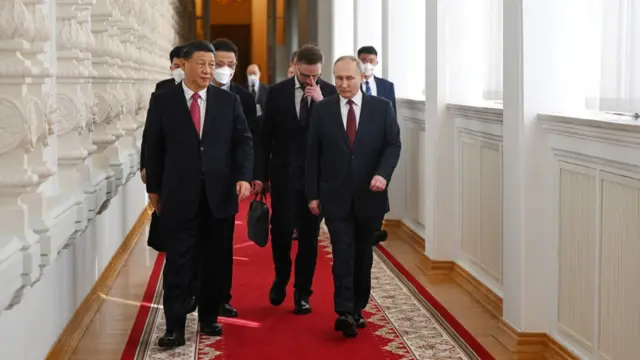 Xi and Putin walk down a lengthy corridor