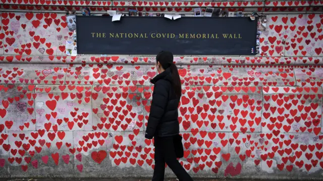 A woman walks past the National Covid Memorial in London