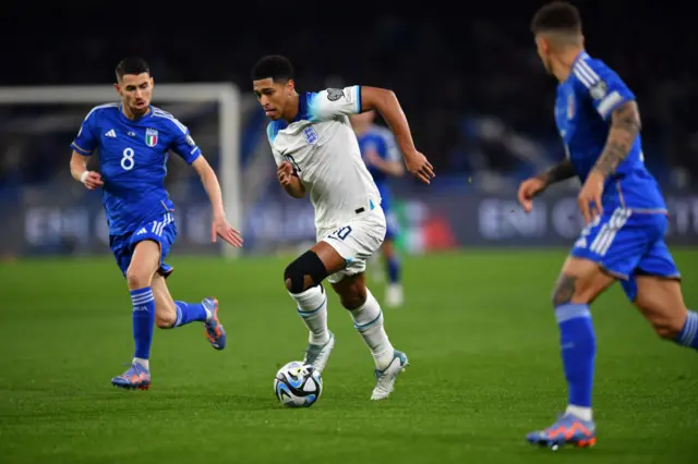 Jude Bellingham of England runs with the ball whilst under pressure from Jorginho