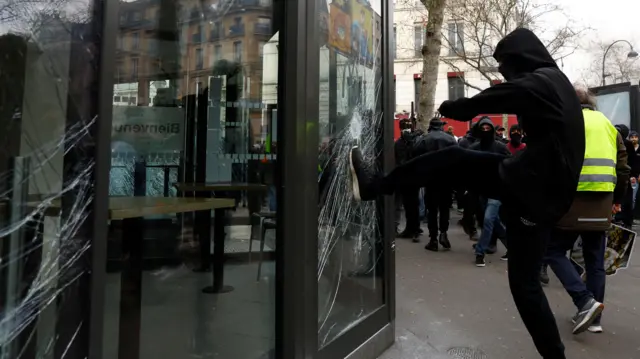 One of the black-clad protesters smashing a McDonald's window