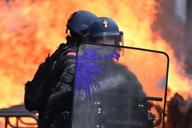 Police stand in front of burning barricades in Paris