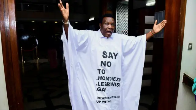 Member of Parliament from Bubulo contituency John Musira dressed in an anti gay gown gestures as he leaves the chambers during the debate of the Anti-Homosexuality bill, which proposes tough new penalties for same-sex relations during a sitting at the Parliament buildings in Kampala