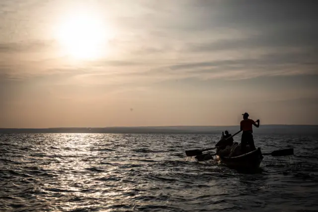 Men fish using a large net on Lake Victoria on August 5, 2022 in Kisumu, Kenya.