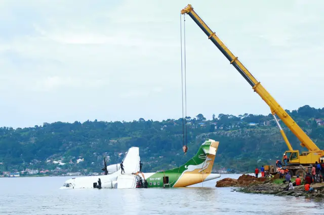 Workers use a crane to pull the crashed Precision Air aircraft out of Lake Victoria in Bukoba, Tanzania, on November 8, 2022