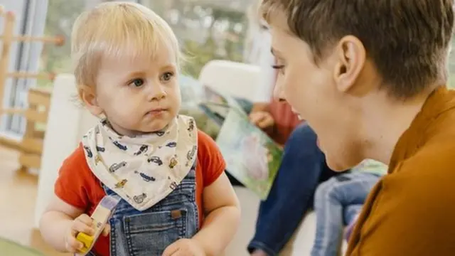 A young woman speaks to a toddler