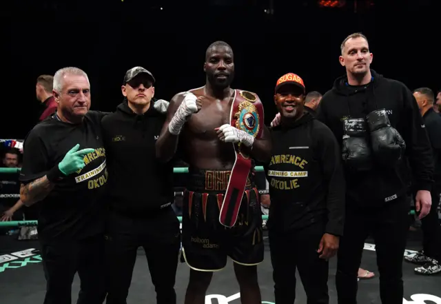 Lawrence Okolie holding his world title with his coaching team